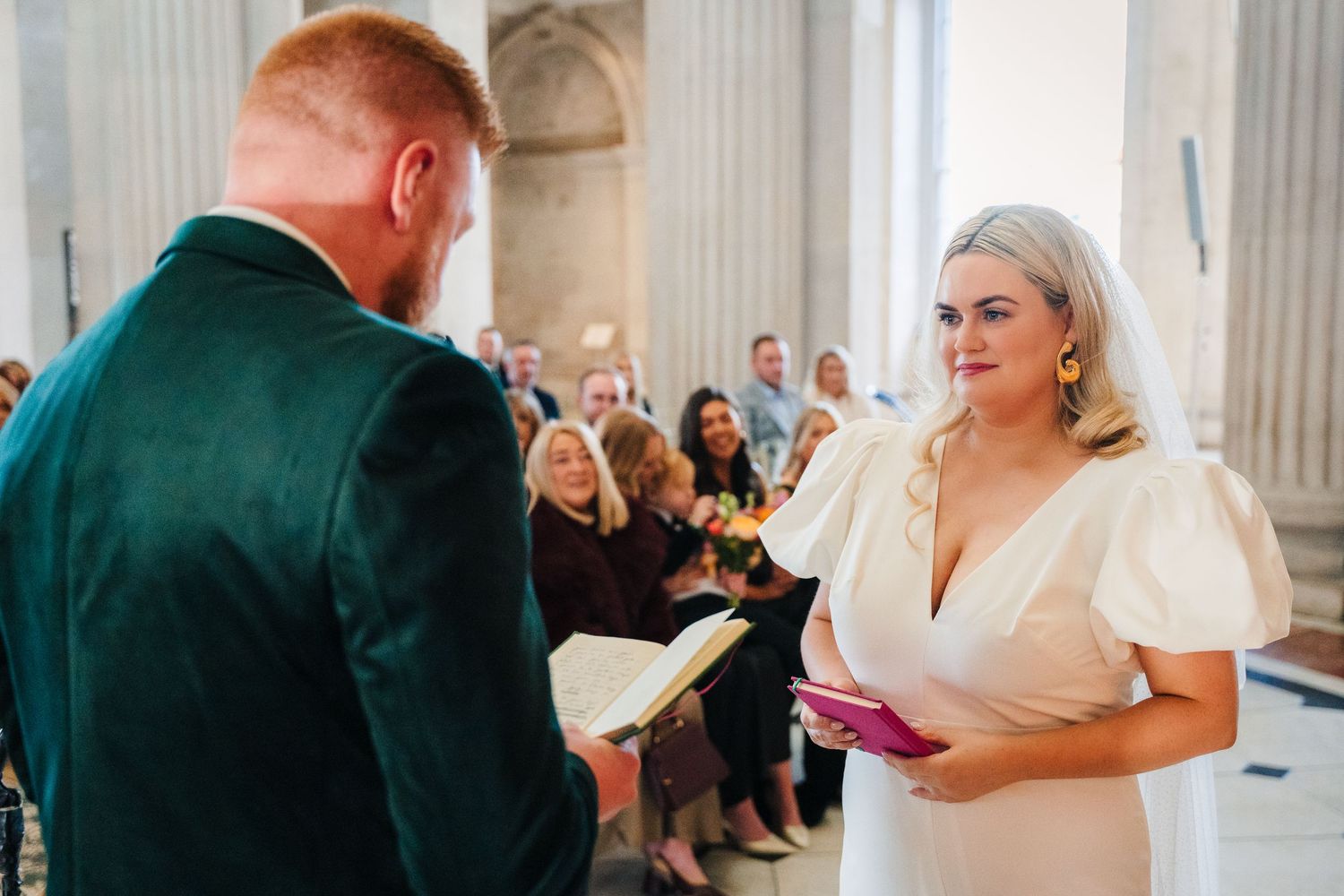 A newlywed couple shares their first dance at an elegant wedding reception with guests looking on in the background. City Hall Dublin Photog