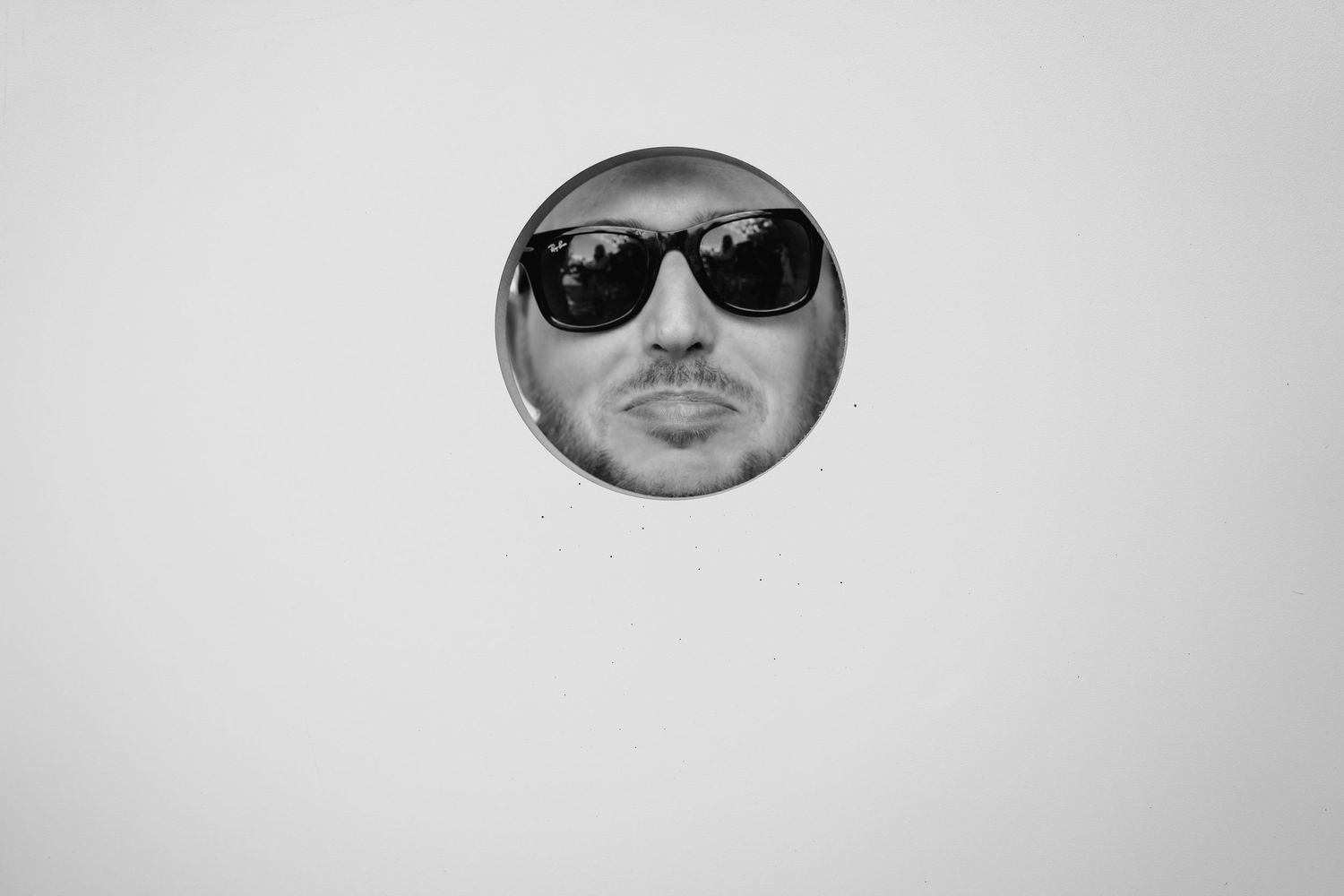 Black and white portrait of someone wearing dark sunglasses against a light gradient background. . Village Barn Tyrrellspass wedding photogr