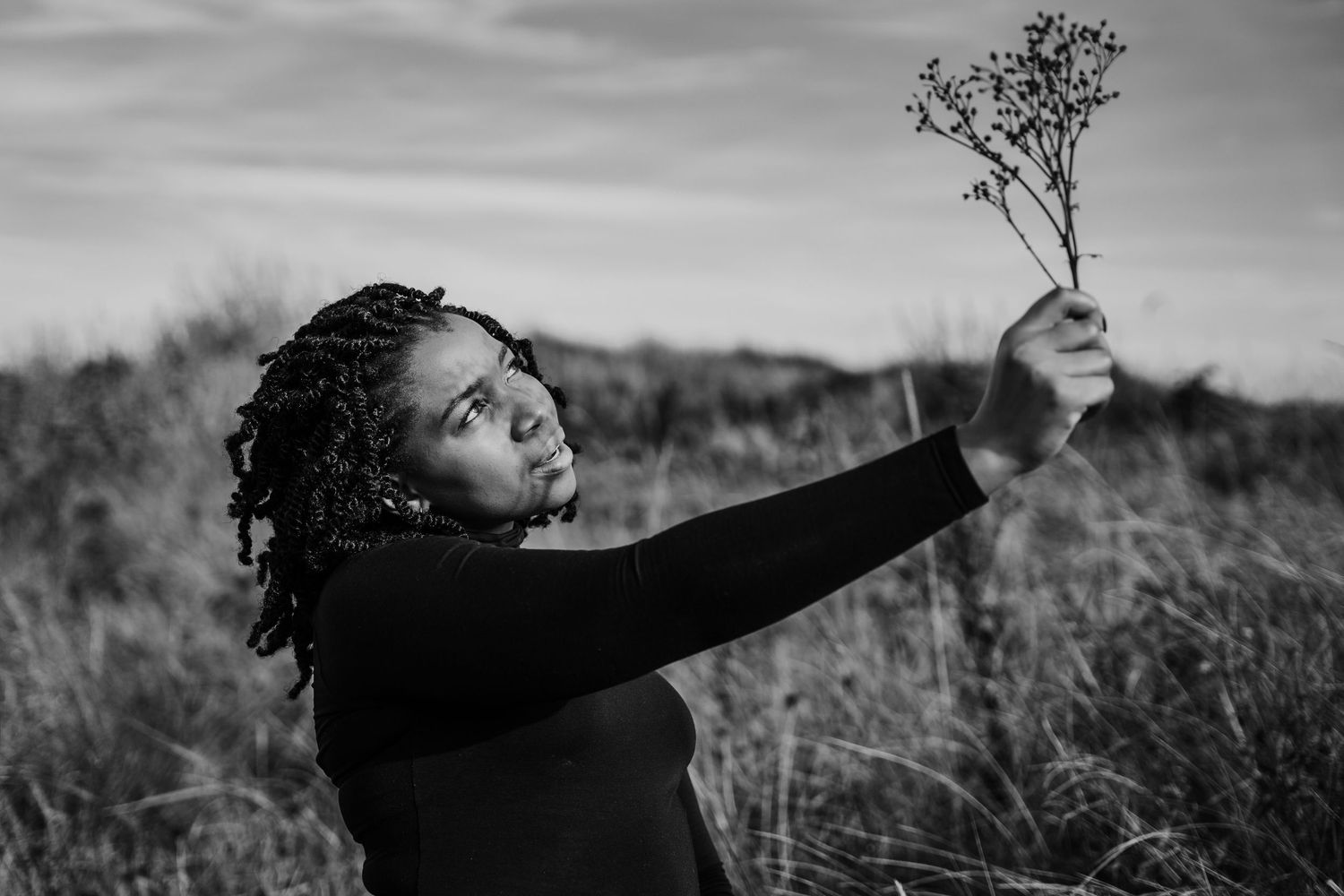 Artistic black and white photo of someone holding a small branch against the sky. Dublin professional headshots photographer
