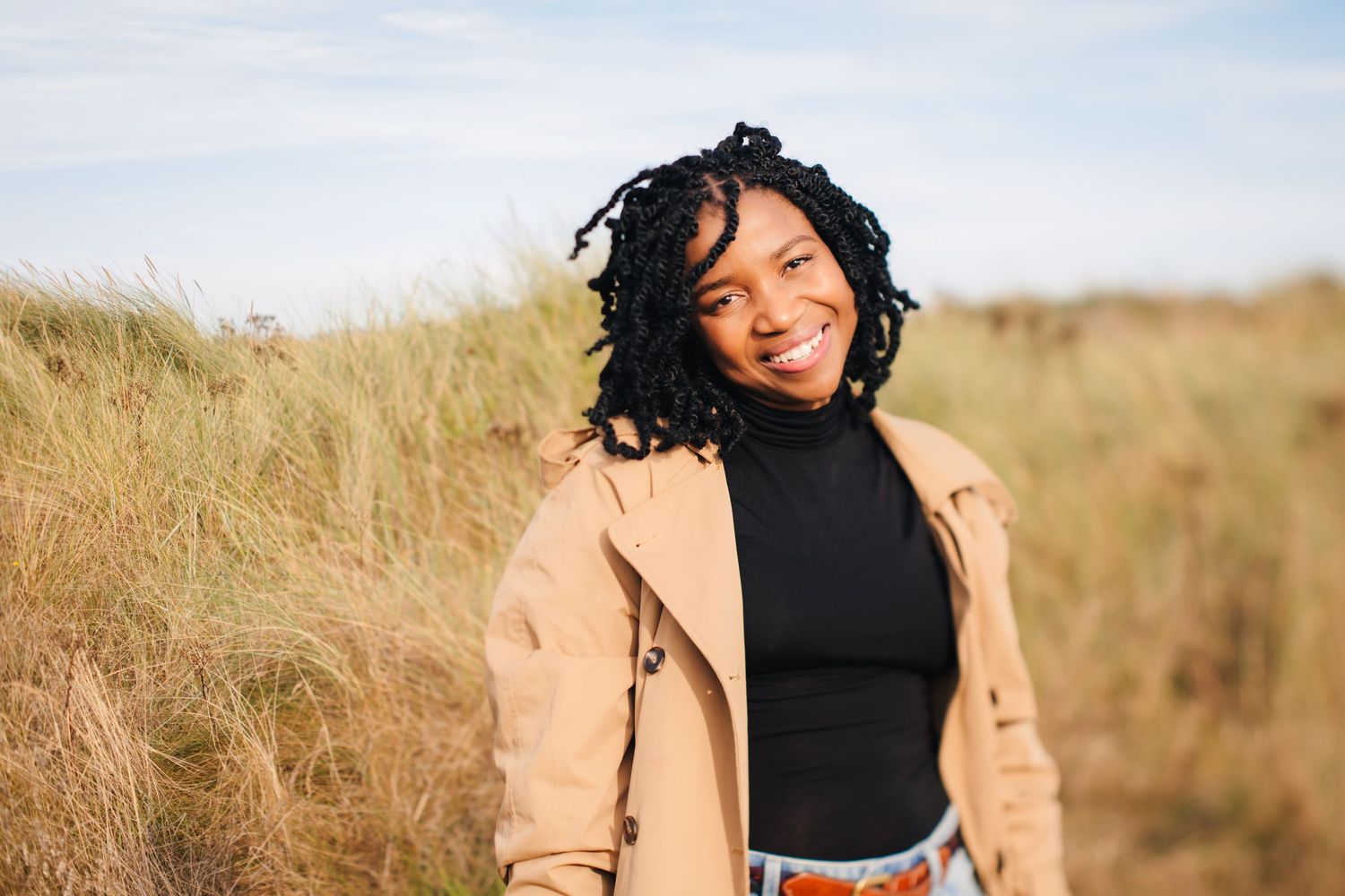 Person in black top and beige jacket poses in natural outdoor setting. Dublin professional headshots photographer