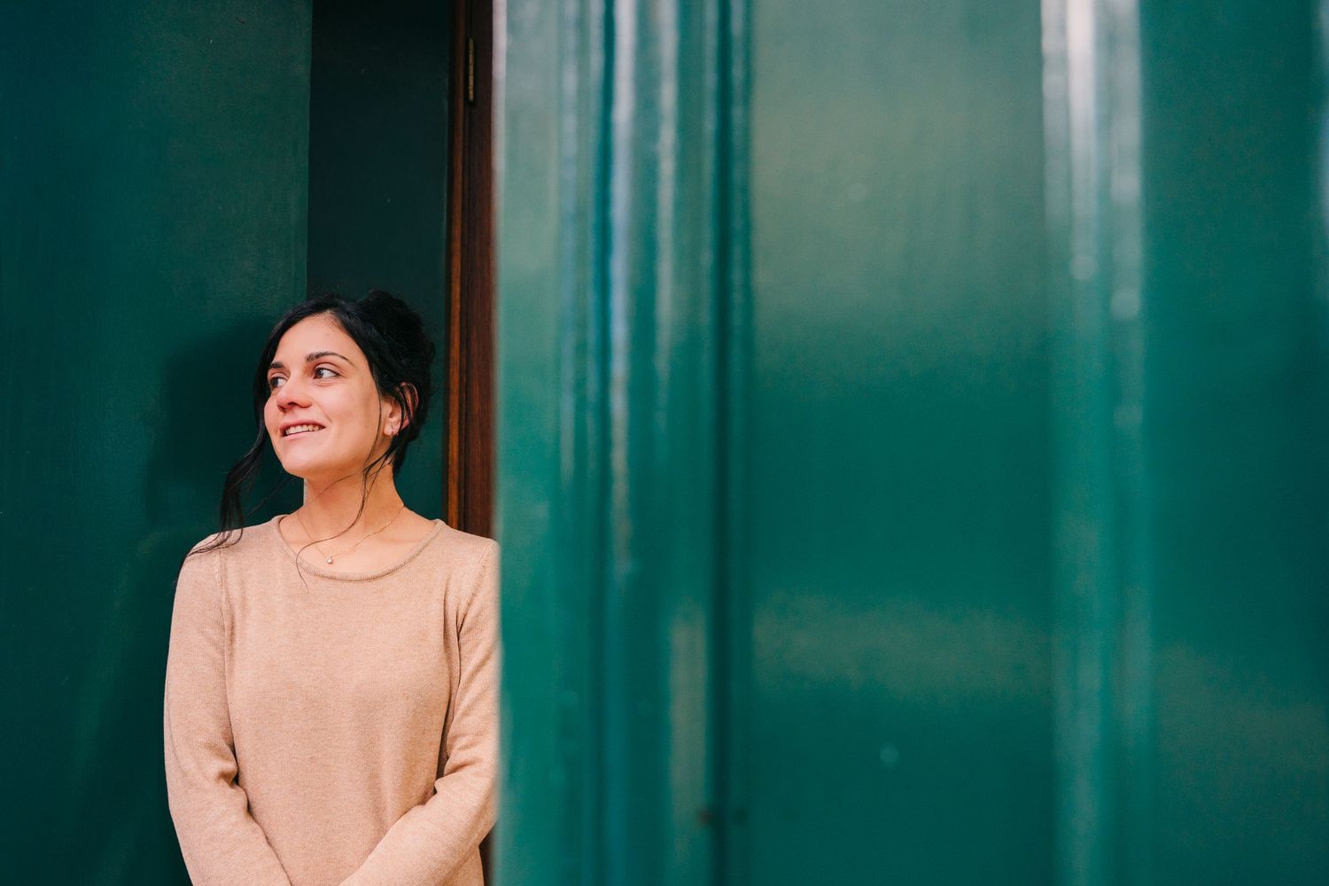 Person in beige sweater standing against turquoise wall in natural lighting. professional headshots dublin
