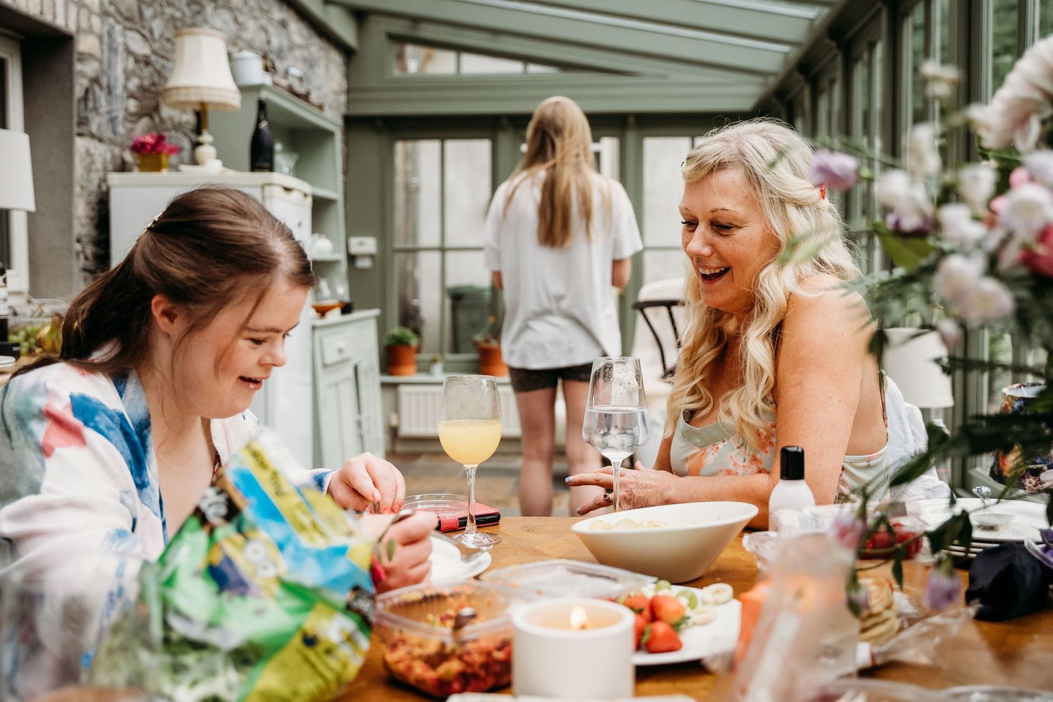 Wedding guests enjoy a casual outdoor meal at long tables decorated with flowers and greenery. Wedding photographer Dublin