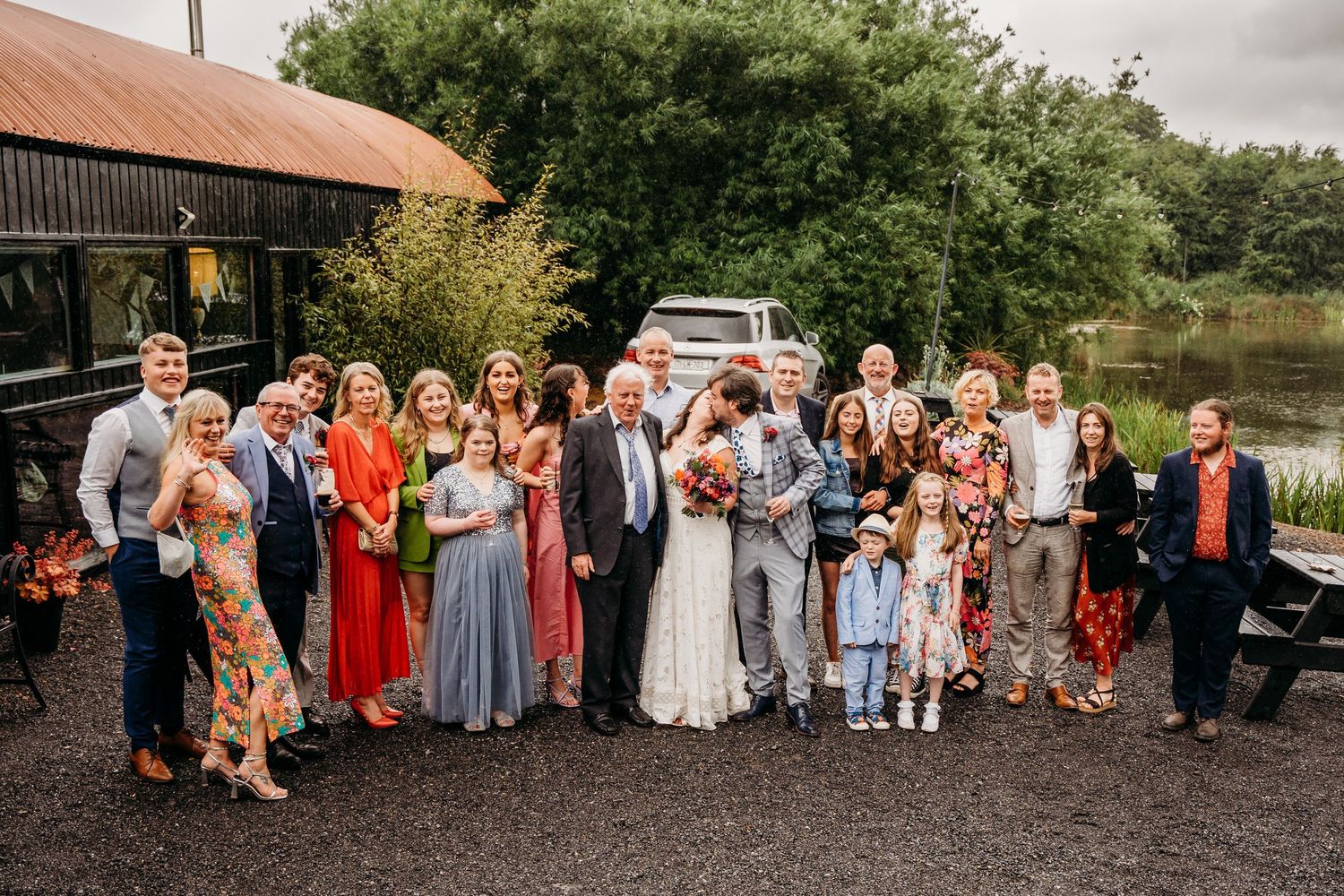 Large group wedding photo of guests lined up outdoors on a cloudy day. Wedding photographer Dublin