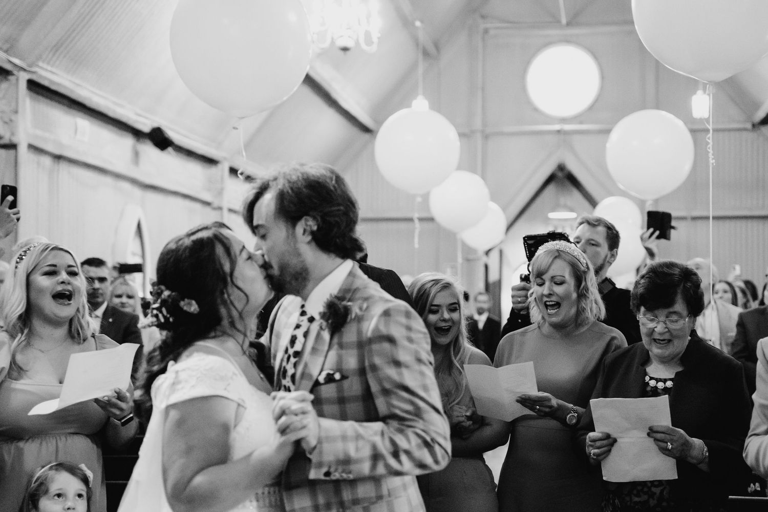 Wedding celebration with white balloons and guests dancing in a festive indoor venue. Wedding photographer Dublin