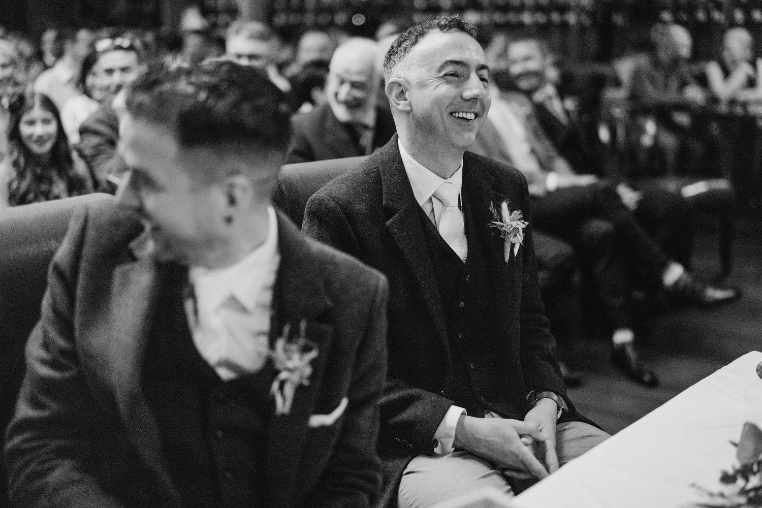 Wedding guests enjoying a candid moment during the ceremony in black and white photography. Marco Pierre Dublin Wedding Photographer