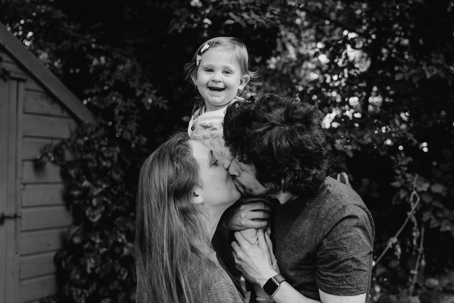 Black and white photo of a loving family sharing a joyful moment together outdoors. family PHOTOGRAPHER Dublin