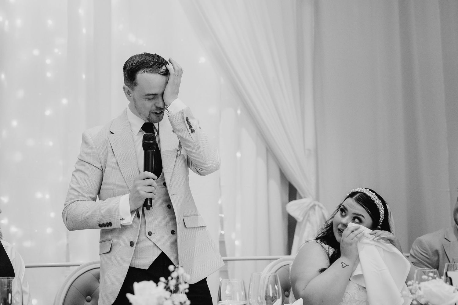 Black and white wedding reception images show guests listening to emotional toasts and raising glasses in celebration. Wedding PHOTOGRAPHER