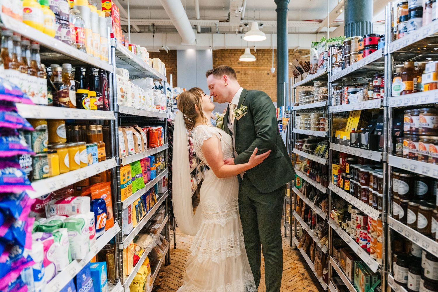 A romantic moment between a couple in wedding attire sharing an embrace in a grocery store aisle. Wedding PHOTOGRAPHER Dublin