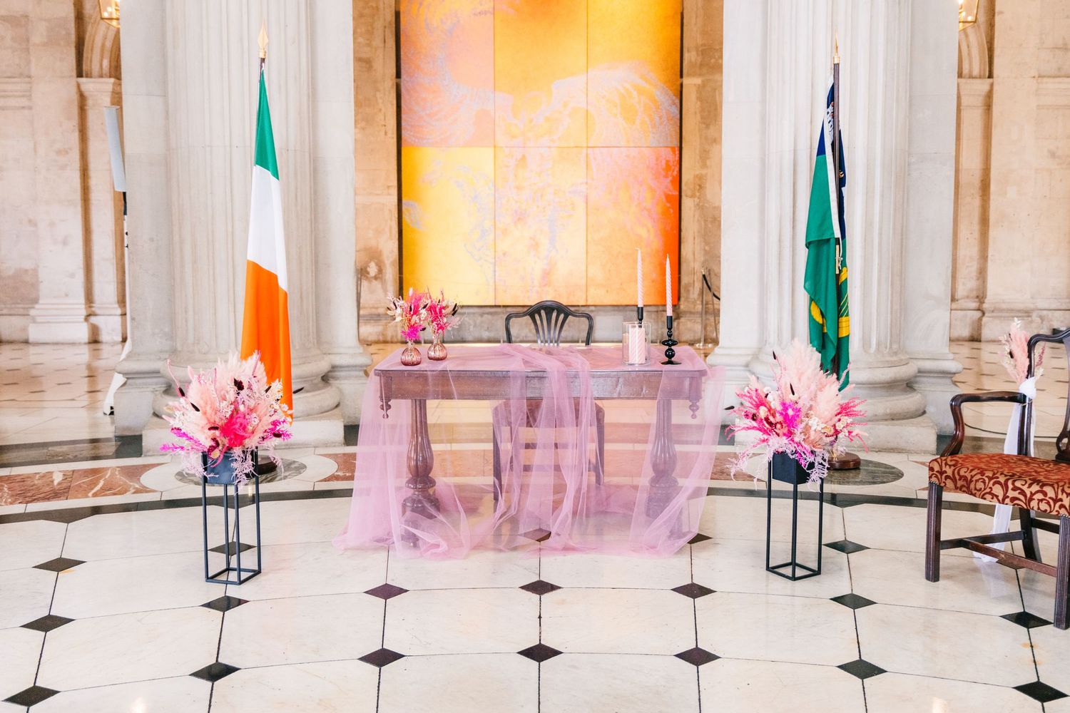 A panoramic view of an elegant marble interior hall with columns and pink floral arrangements.  city hall dublin wedding photos