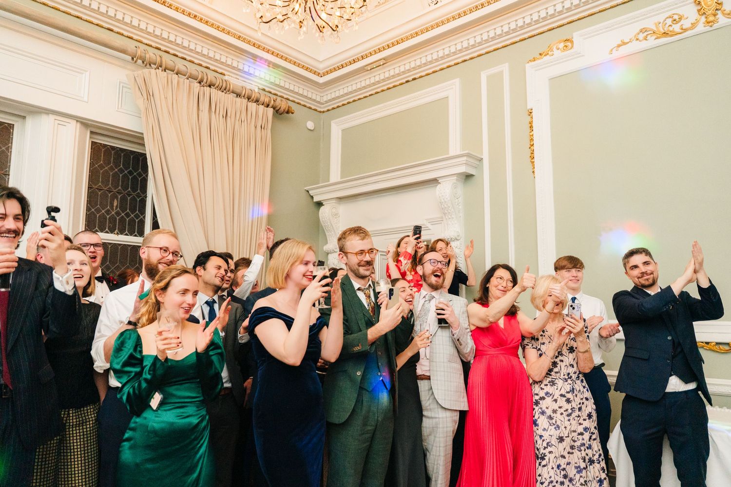 Wedding guests in formal attire take photos during reception in grand ballroom. Stephens green club dublin Wedding photographer