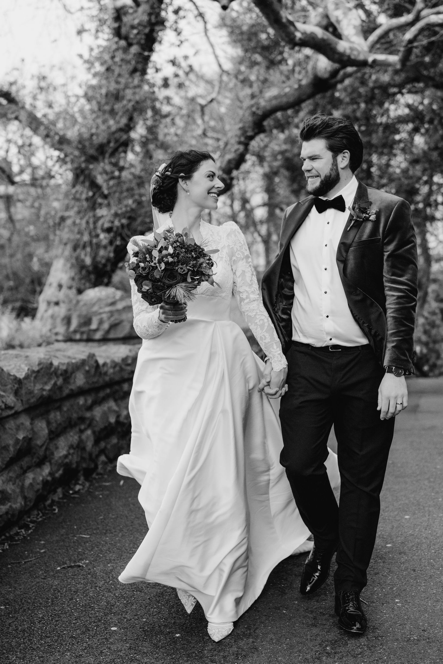 A wedding couple walks together on a garden path, with the bride's dress flowing in the breeze. Stephens green club dublin Wedding photograp