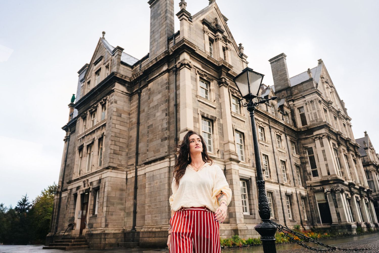 Lifestyle photoshoot featuring red striped pants and white top against gothic architecture backdrop. professional headshots dublin
