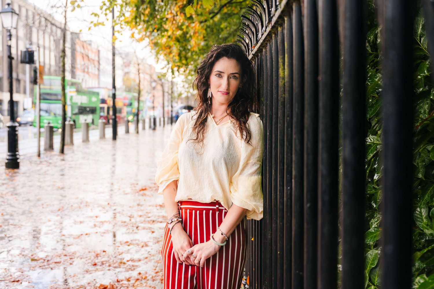Autumn leaves scatter along an iron fence walkway in an urban setting. professional headshots dublin photographer
