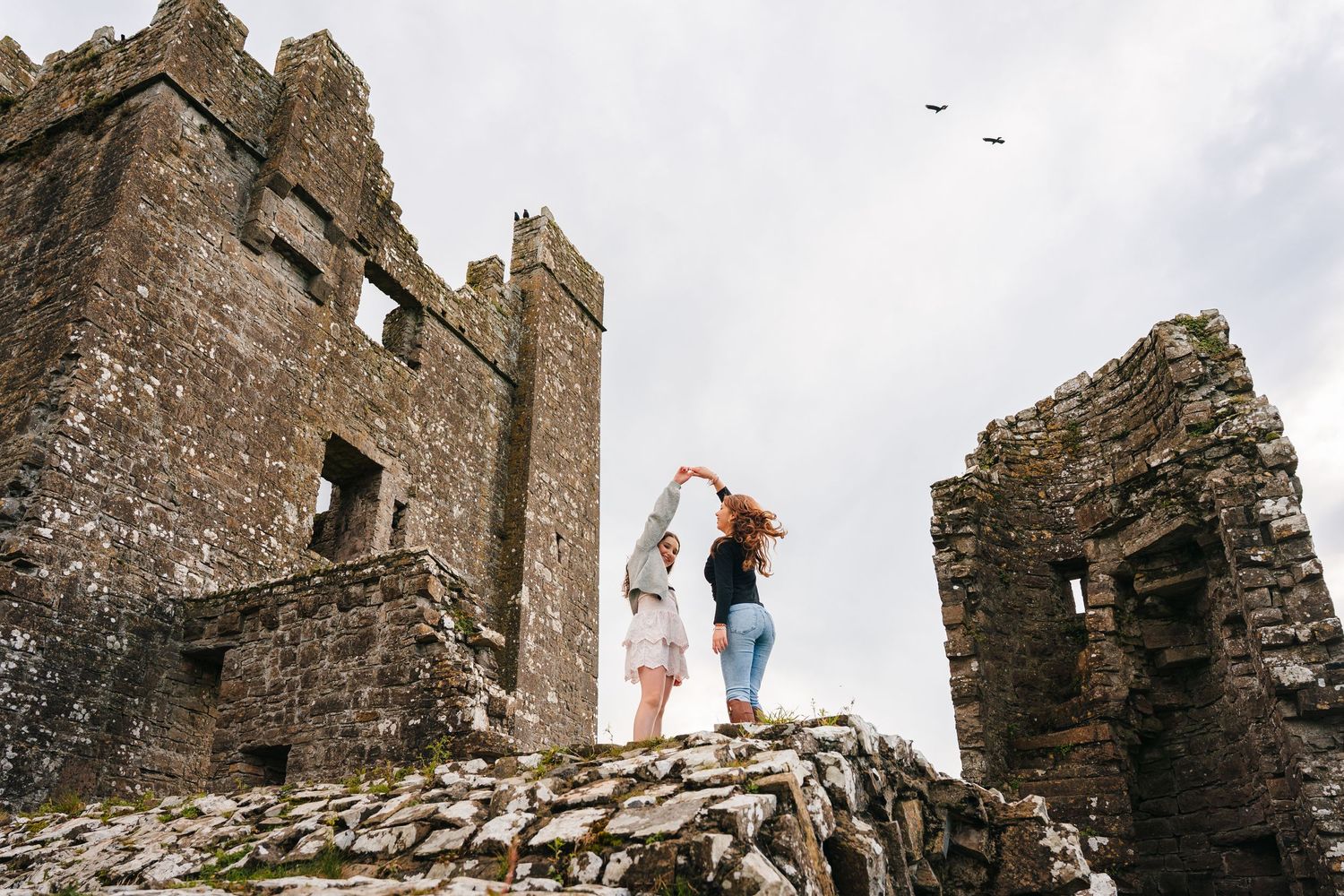 Ancient castle ruins stand dramatically against a cloudy sky in Ireland.