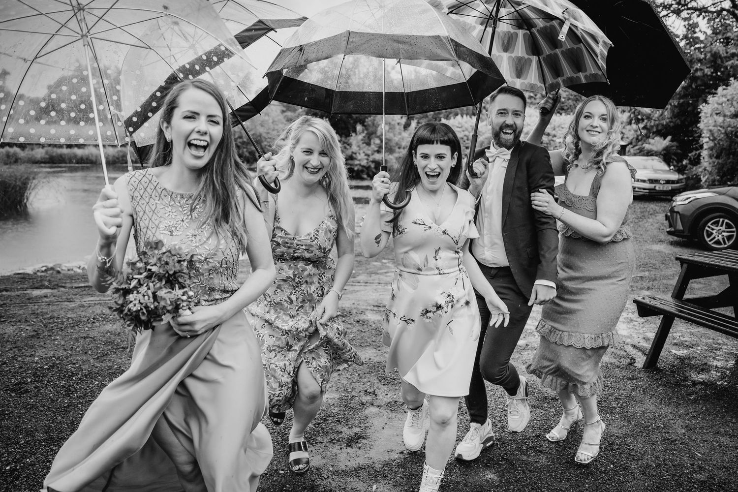 Black and white photo of wedding guests dancing and celebrating outdoors with natural scenery. Wedding photographer Dublin