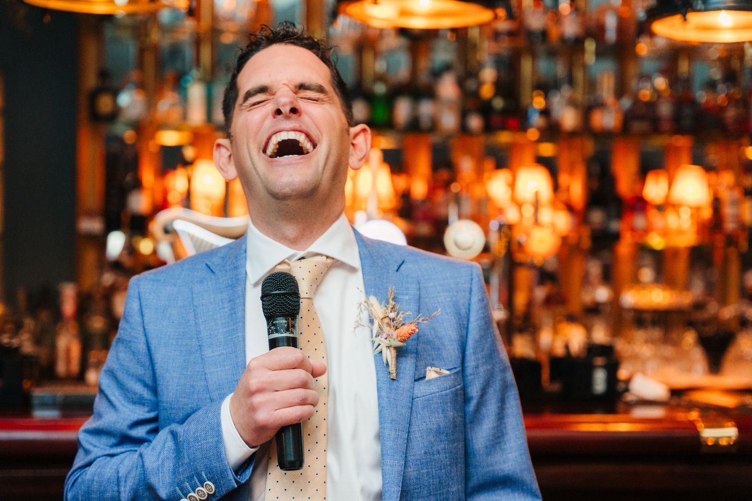 People laughing and celebrating at a bar with warm ambient lighting. Marco Pierre Dublin Wedding Photographer