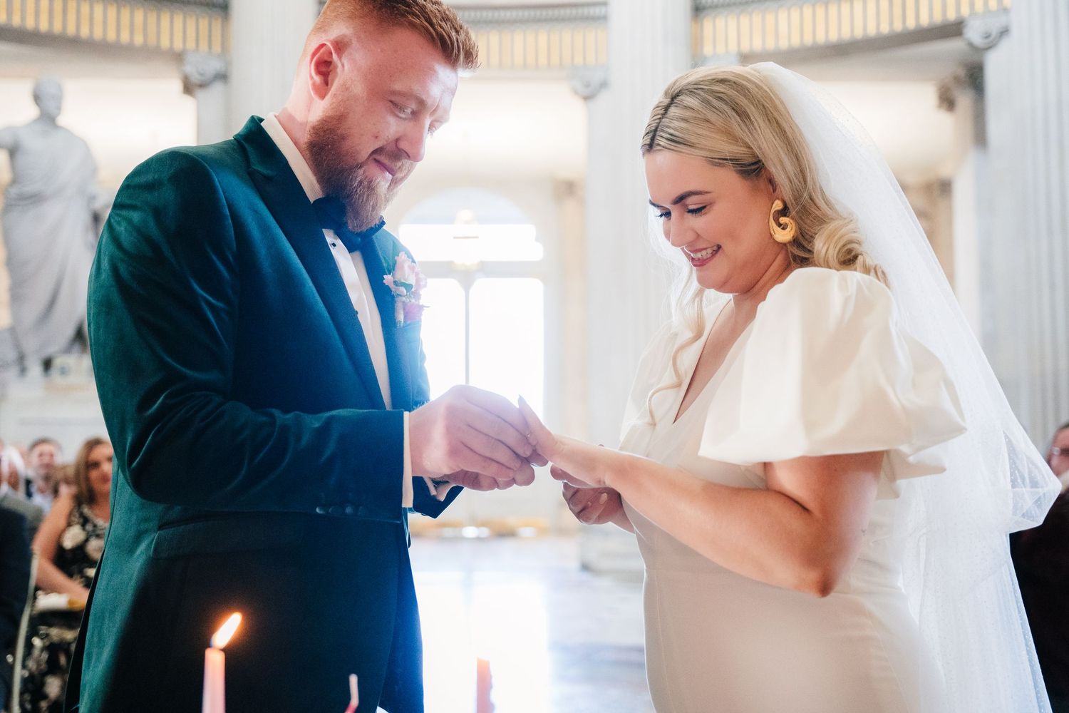 Couple exchanges rings during intimate wedding ceremony in elegant white columned venue. City Hall Dublin Photographer