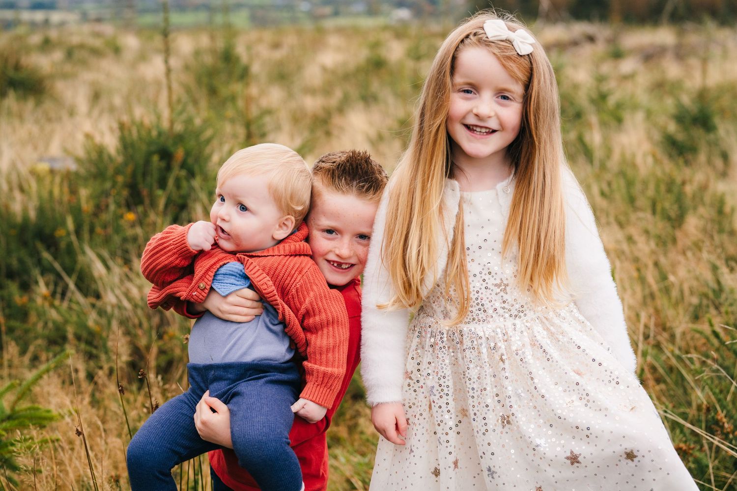 Family Photographer Dublin Ireland Natural outdoor autumn family photos show joyful moments and genuine smiles in golden grass field.