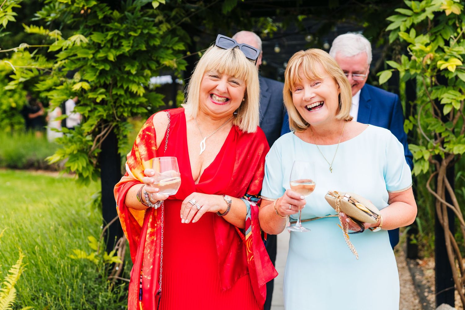 Poulaphouca Wedding photographer wicklow  Wedding guests laughing and smiling together outdoors in a garden setting with lush greenery.