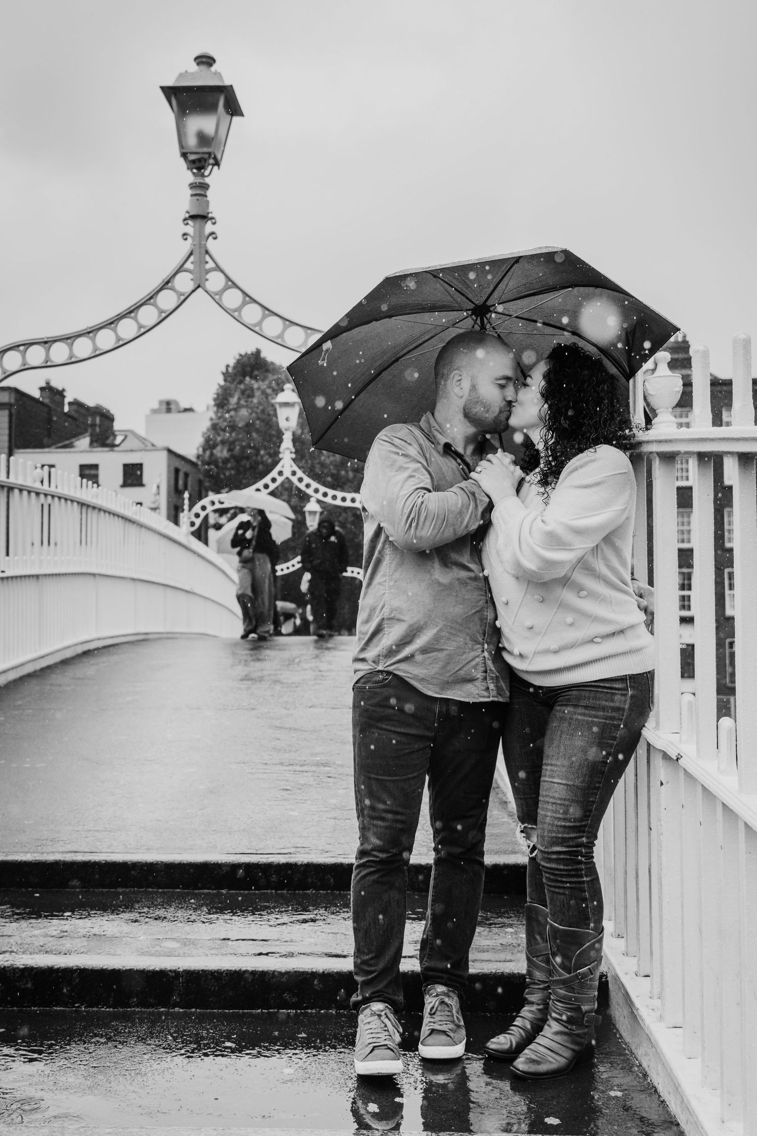 Black and white photos of couple embracing on a white bridge in the rain. Proposal Dublin Photographer PHOTOGRAPHER Dublin