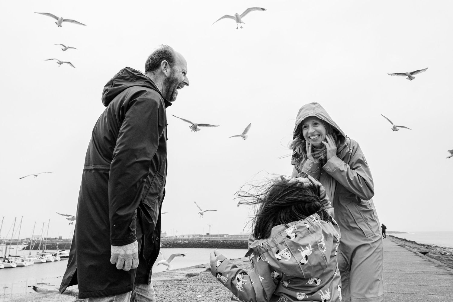 People watching seagulls flying against white sky by waterfront. PHOTOGRAPHER Dublin