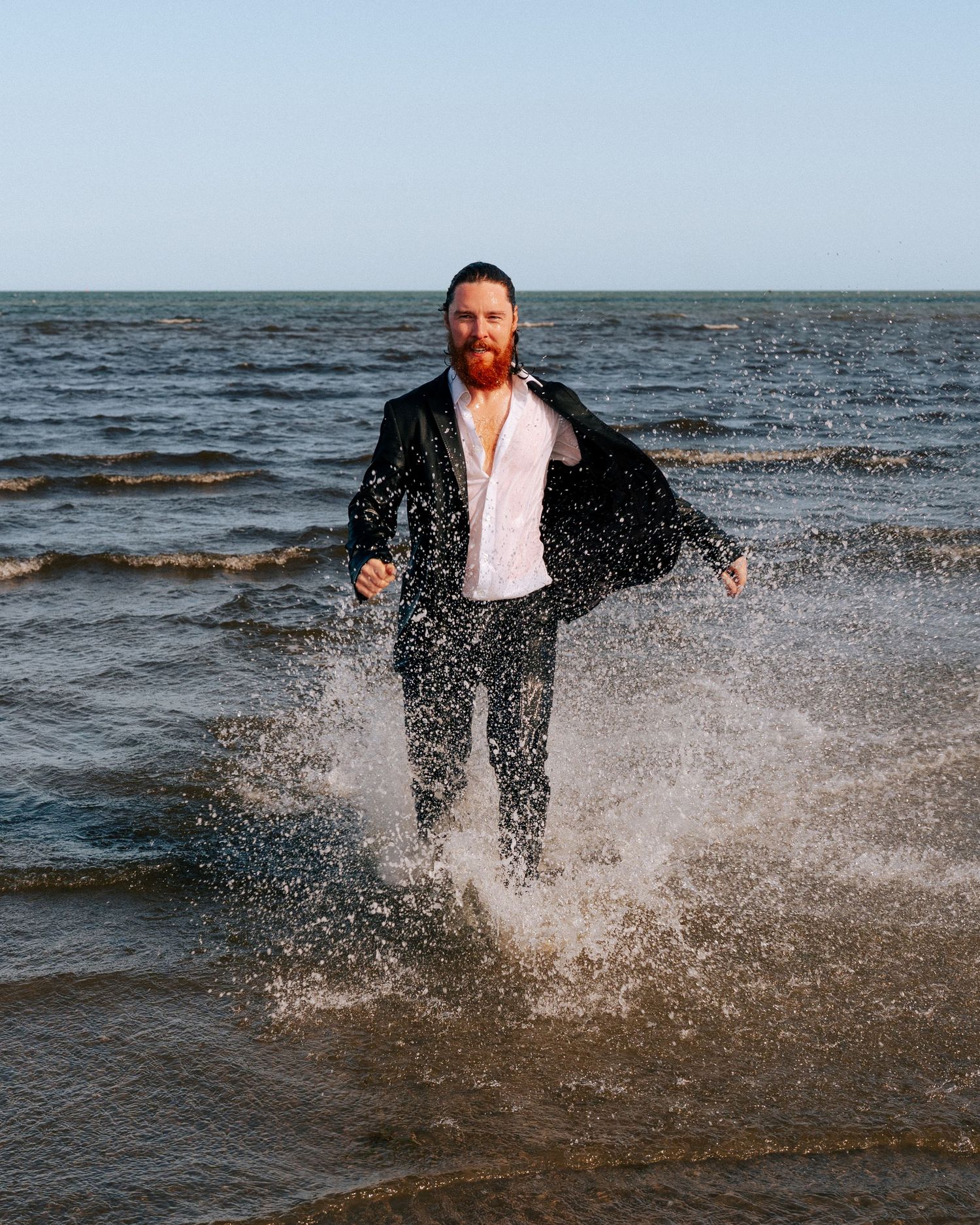 Someone splashes through shallow ocean water wearing formal attire on a sunny day. PHOTOGRAPHER Dublin