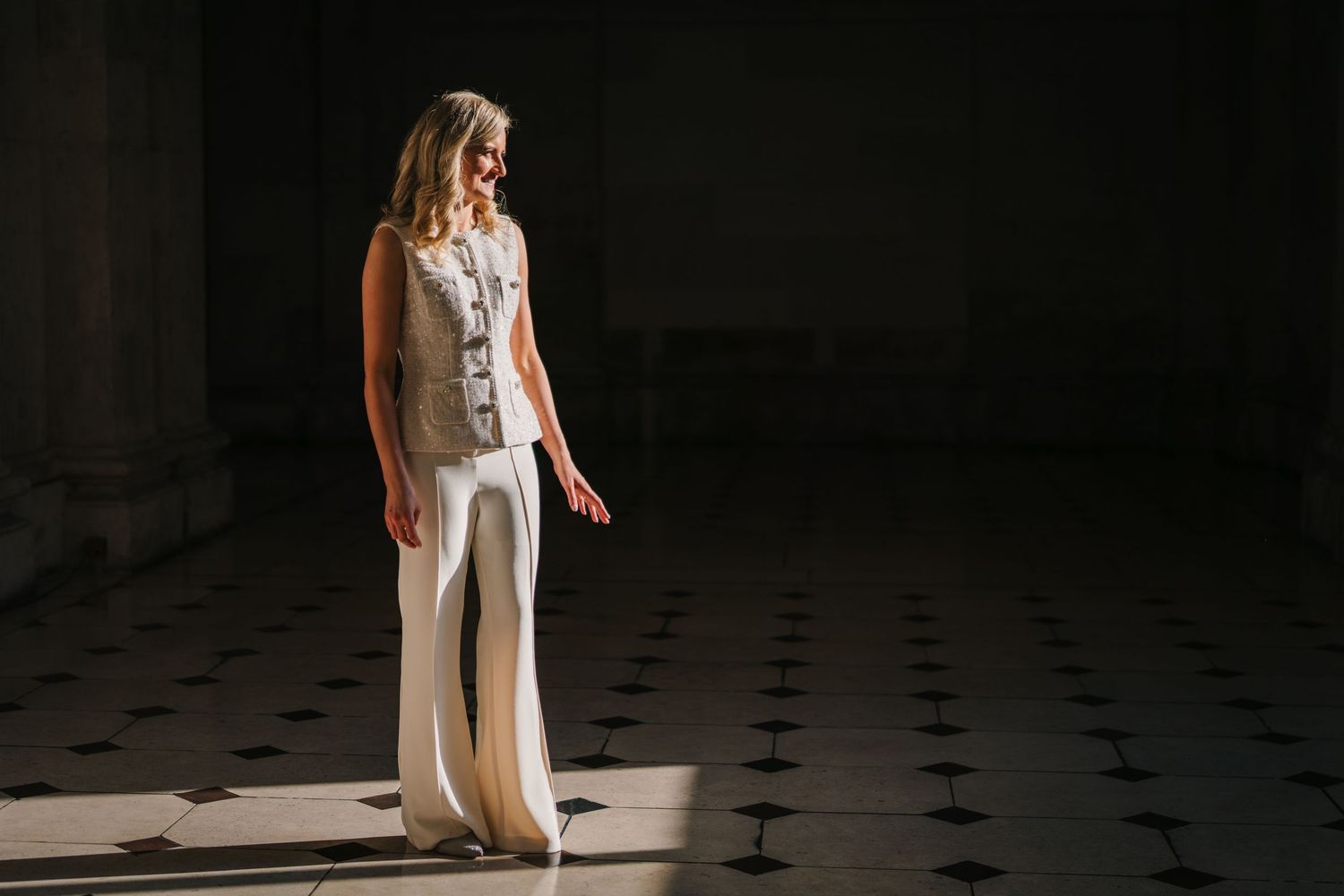 Bride in modern white jumpsuit poses dramatically in checkered floor space. City Hall Dublin wedding photogrAPher