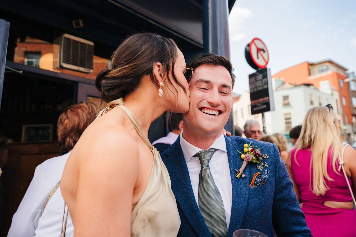 An affectionate moment captured at an outdoor celebration with guests in formal attire. Same sex wedding PHOTOGRAPHER Dublin