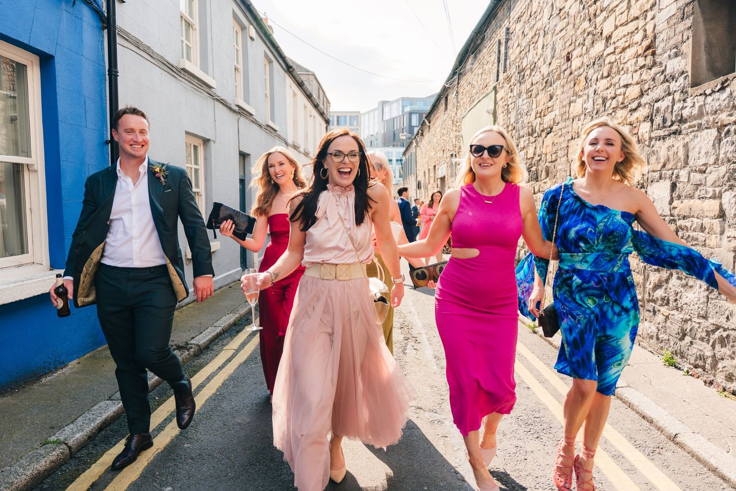 Wedding guests walking down a charming narrow street with stone walls. Same sex wedding PHOTOGRAPHER Dublin