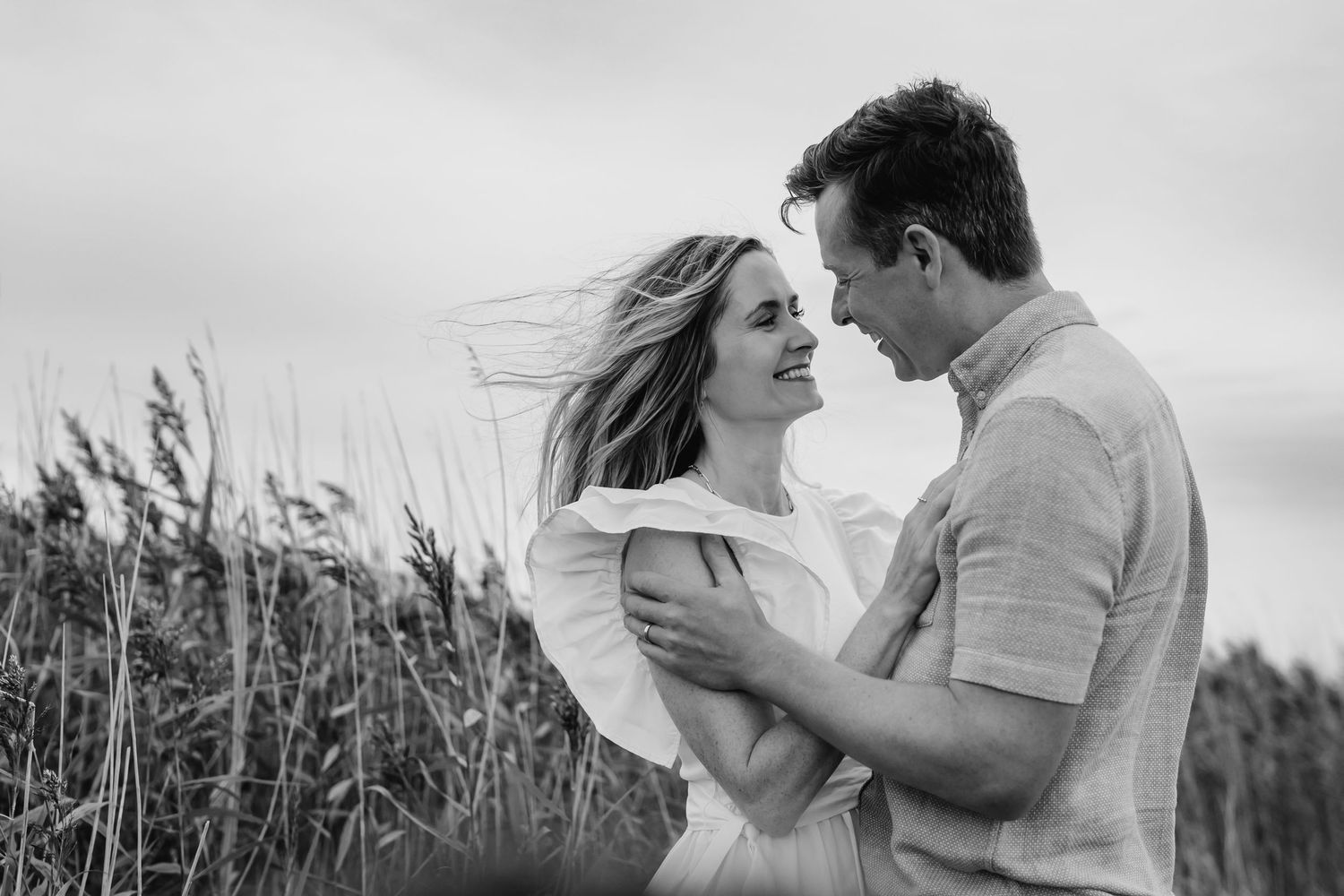 Black and white romantic photos showing a couple embracing and kissing in a rustic outdoor field setting. Couple's photographer Dublin Irela