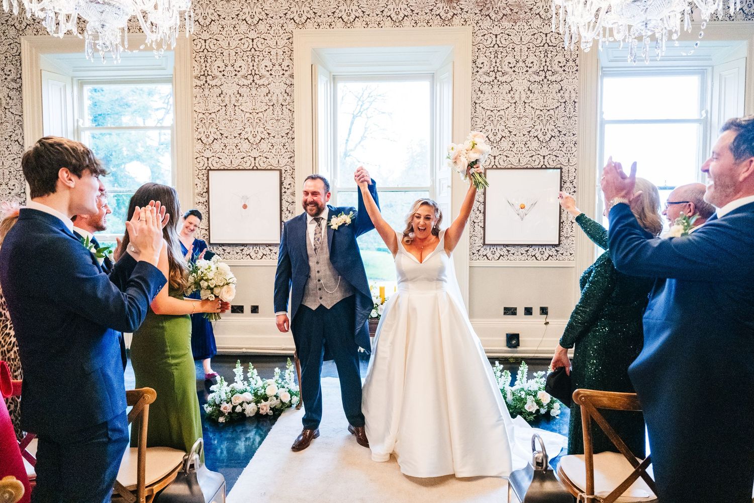 Wedding guests dancing and celebrating on a dance floor with chandelier lighting in an elegant ballroom setting.  Virginia Park Lodge Weddin
