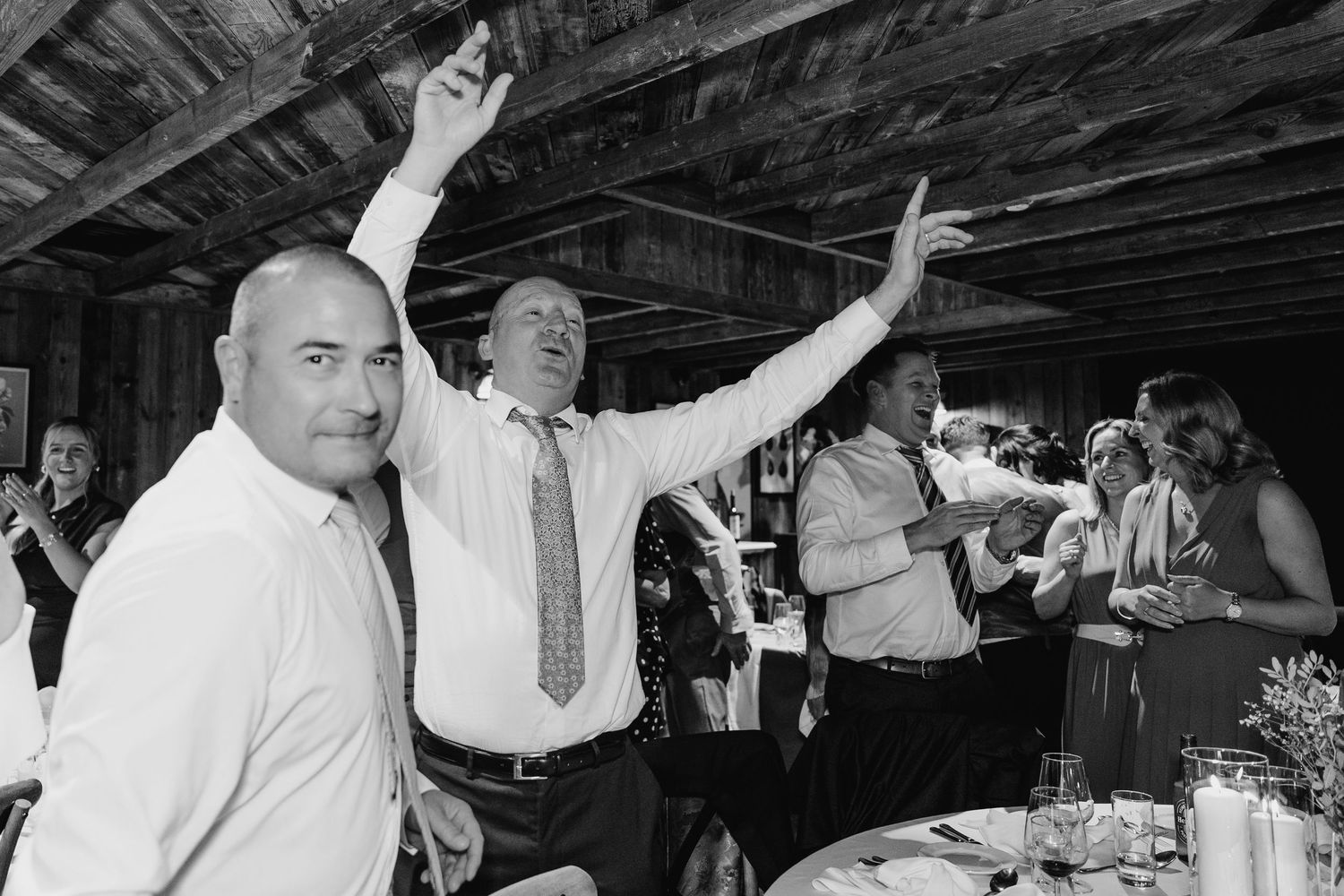 Wedding party dances under wooden beams at a rustic indoor celebration. The Dean Dublin Wedding Photographer