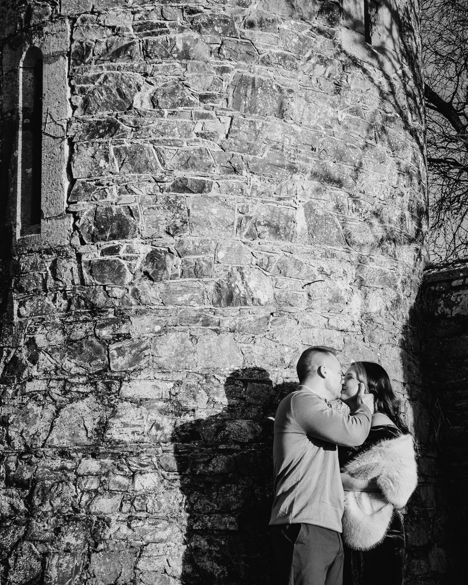 A romantic moment between a couple against an old stone wall in black and white. PHOTOGRAPHER Dublin ireland