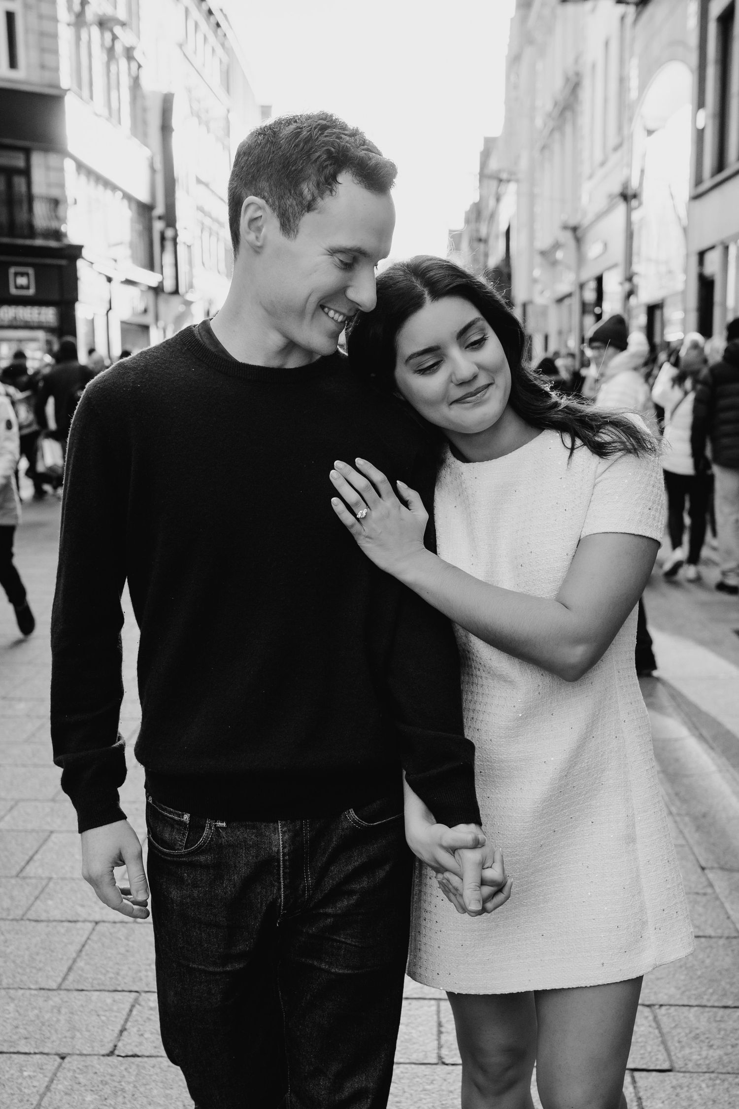 A couple laughs together while walking down a European city street in black and white. PHOTOGRAPHER Dublin ireland