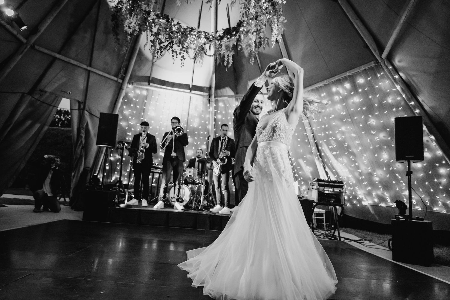 A wedding reception dance floor moment captured in black and white as couples dance beneath elegant lighting. Wedding PHOTOGRAPHER Dublin