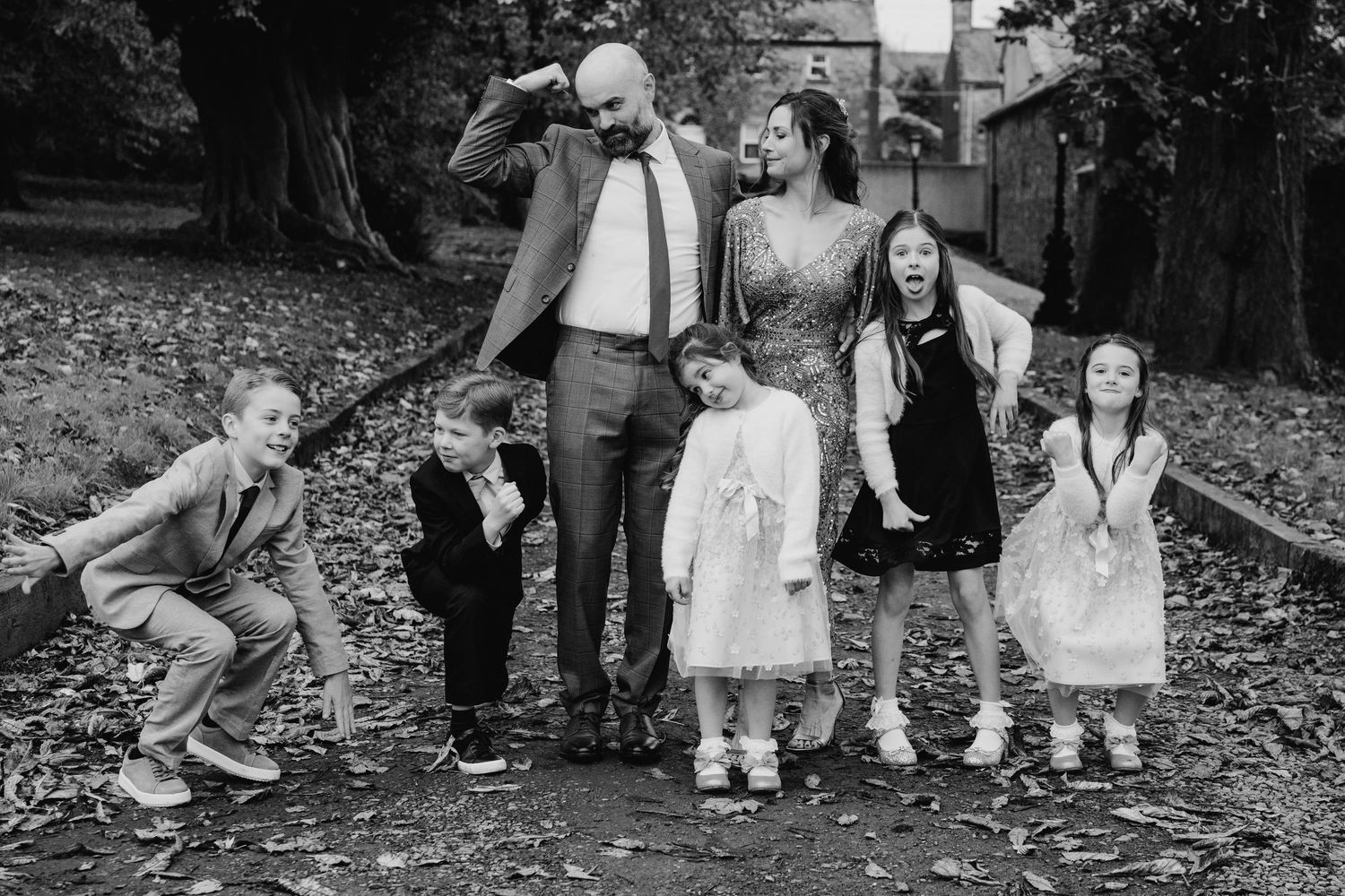 A group of people wearing casual attire sit together outdoors on a garden path while taking a casual photo. Wedding PHOTOGRAPHER Dublin