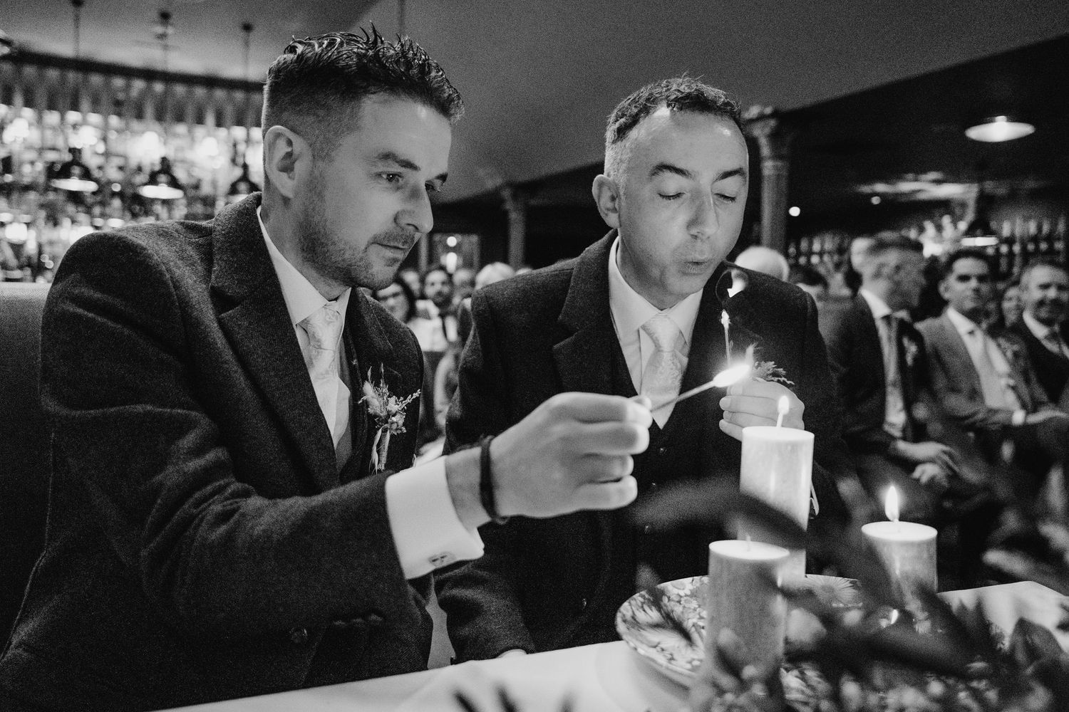 Two guests in suits share drinks at a dimly lit bar in black and white. Marco Pierre Dublin Wedding Photographer