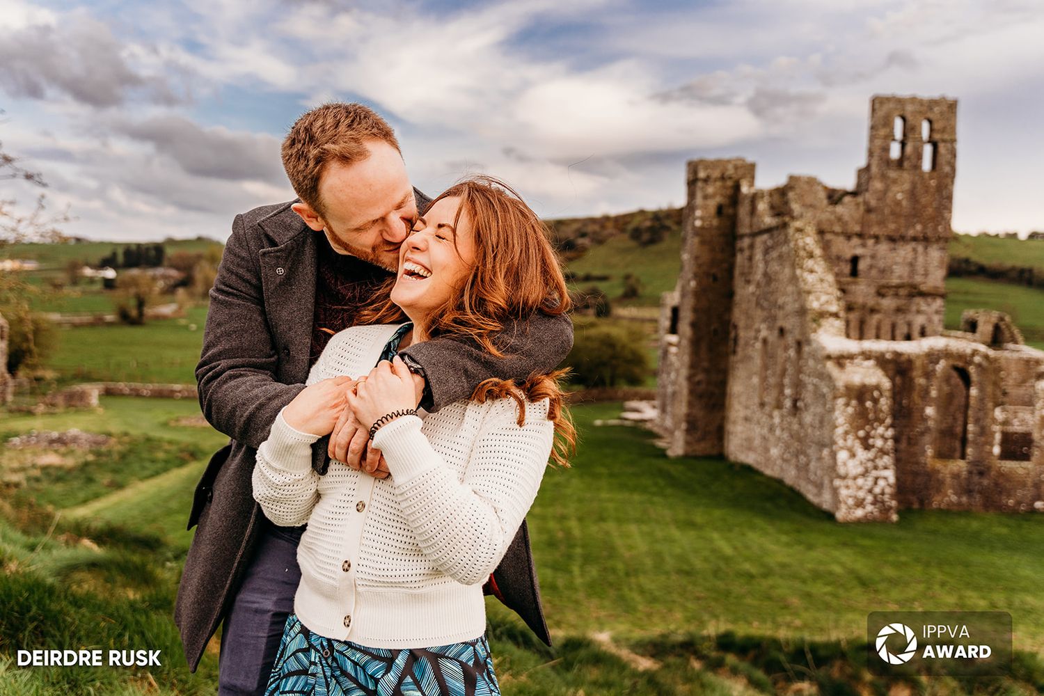 A couple sharing a joyful moment in front of ancient castle ruins in the countryside. Family PHOTOGRAPHER Dublin PHOTOGRAPHER Dublin