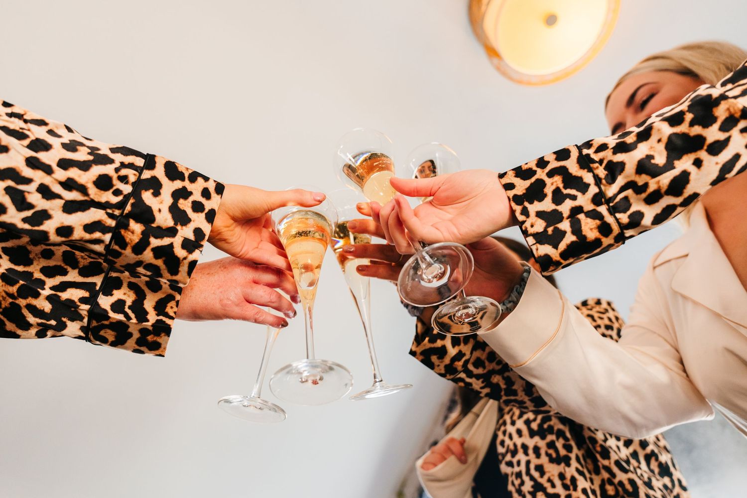 A hand in a leopard print sleeve holds a champagne glass against a white background. Wedding photographer dublin