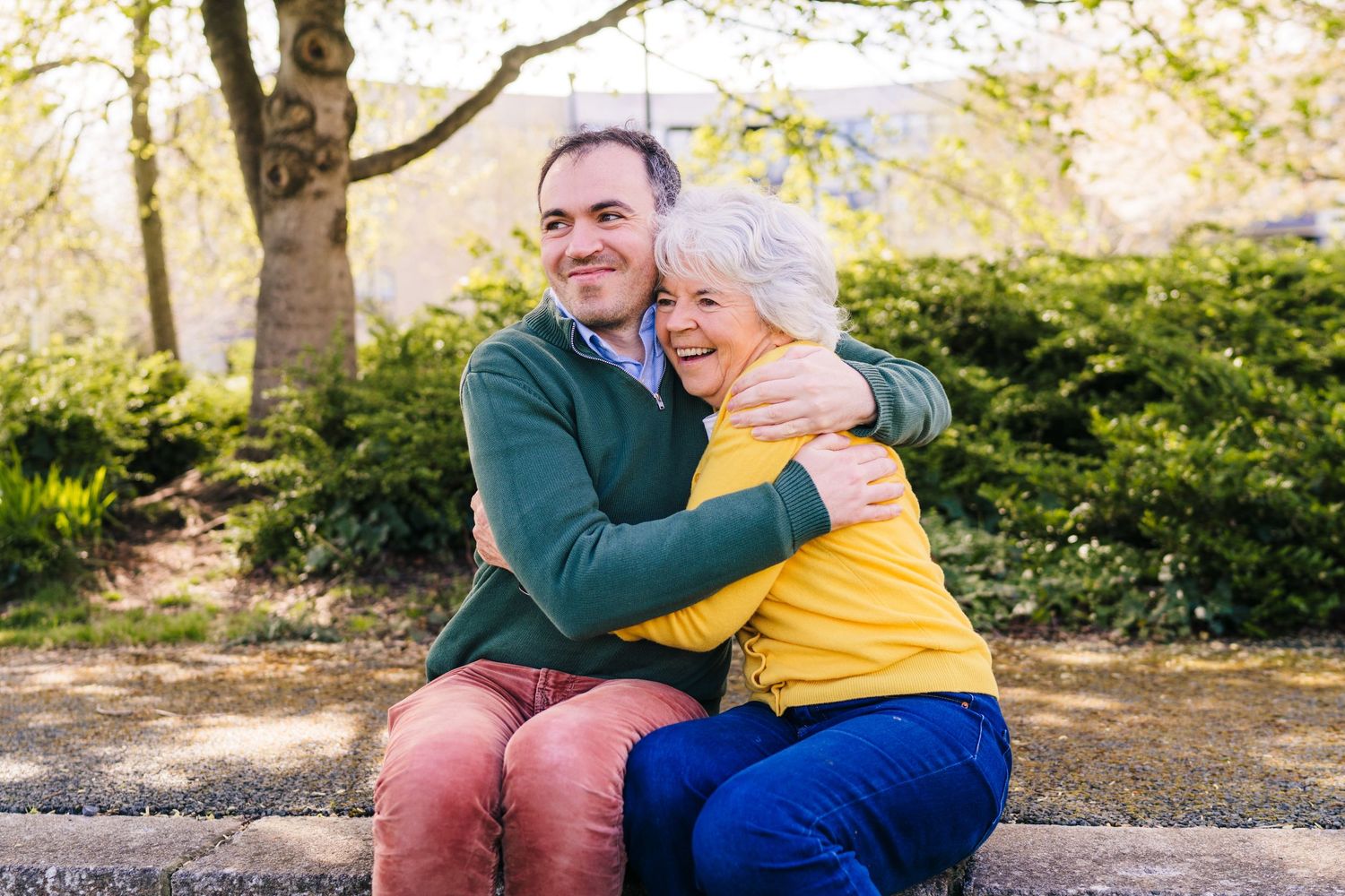 Senior couple sitting together on a bench in a park during autumn enjoying a tender moment. Family photographer Dublin