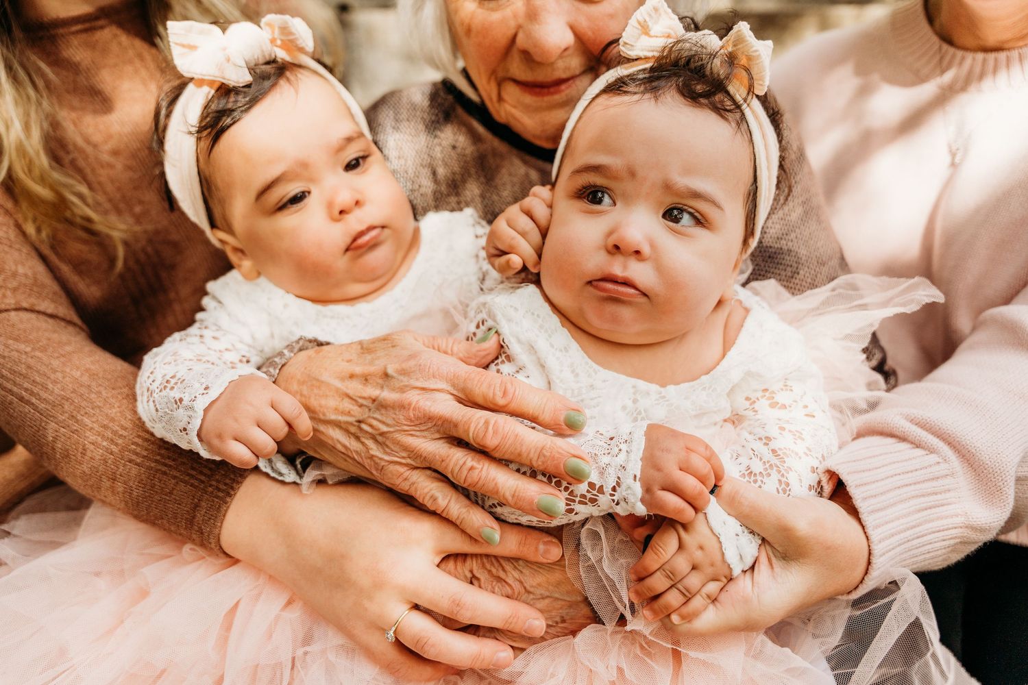 Gentle hands lovingly interact with a smiling baby wearing soft pink clothing. family PHOTOGRAPHER Dublin