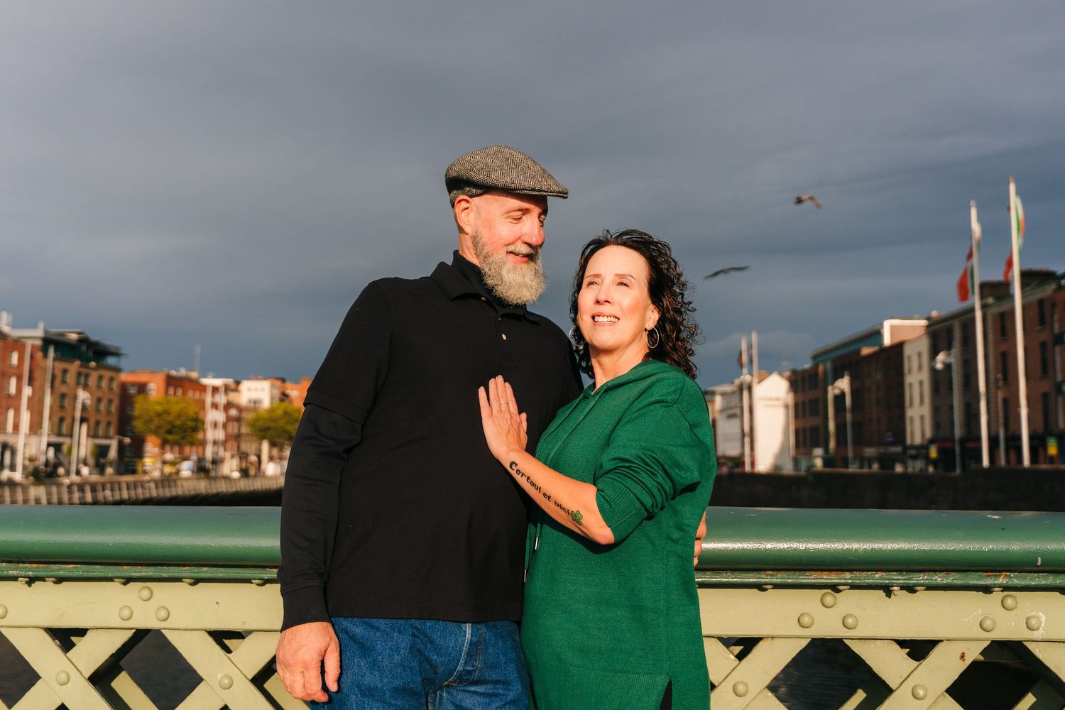 Two people embrace on an ocean pier at sunset while birds fly overhead in Newport Beach. PHOTOGRAPHER Dublin