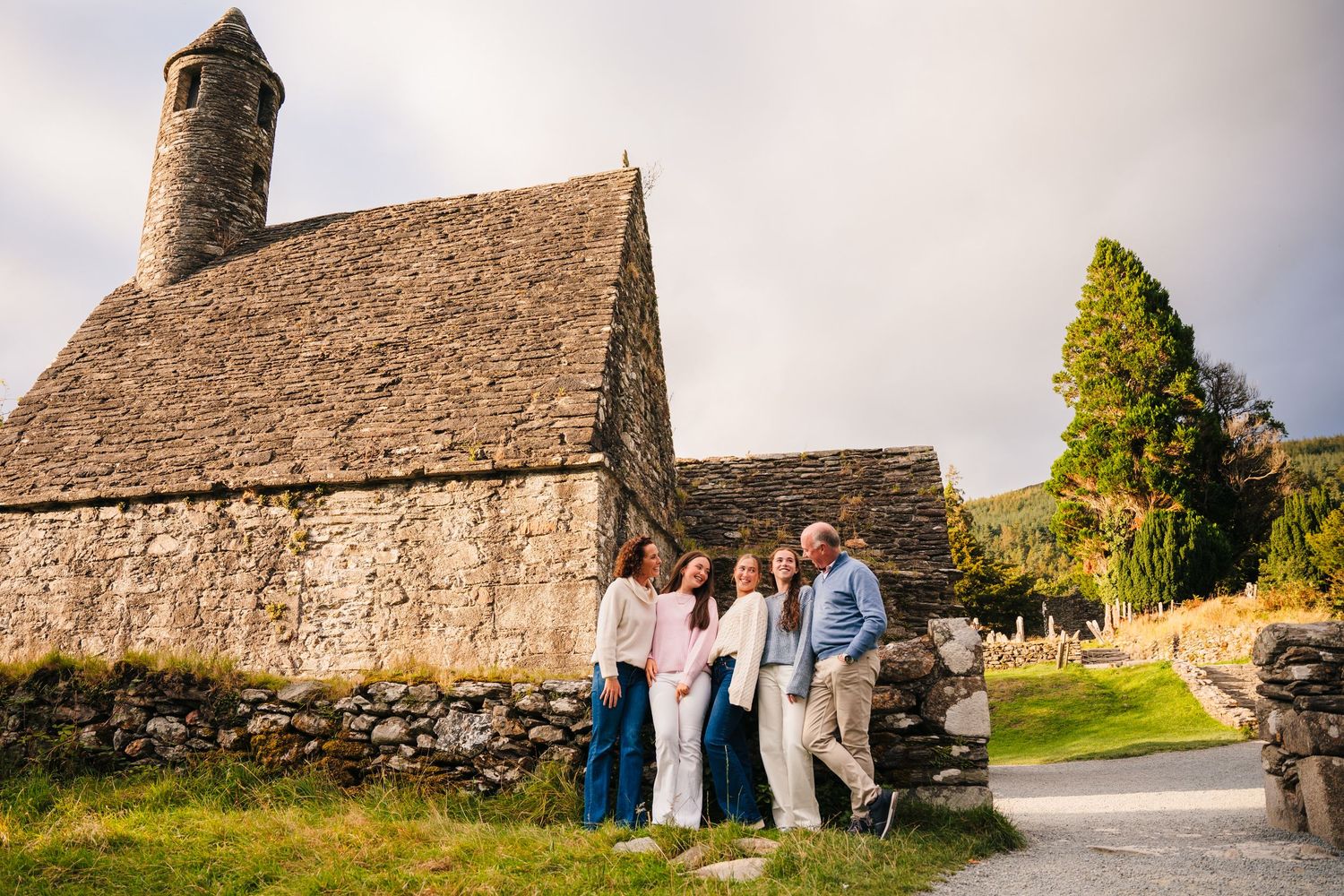 Family photographer Ireland Dublin Family gathering in front of an ancient stone church with thatched roof in Ireland.