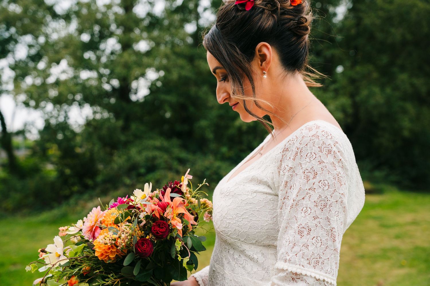 Bride in lace dress holds vibrant autumn bouquet during outdoor photo session.Wedding Photography Trim Castle Ireland