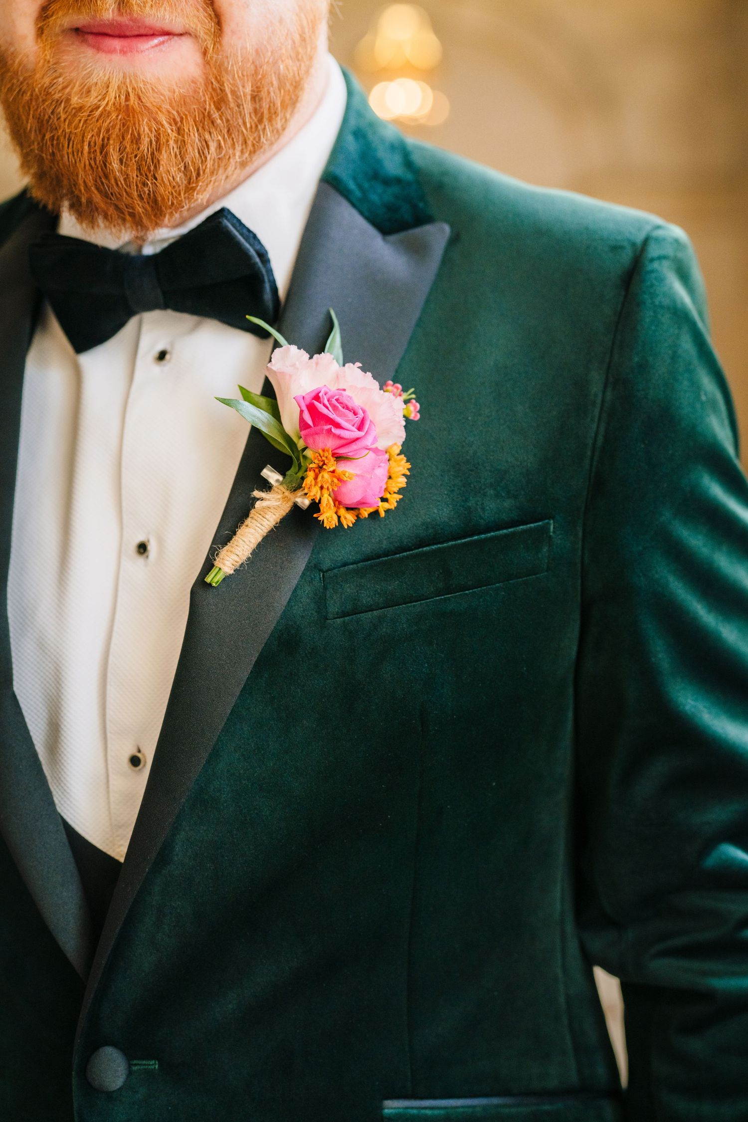 Close-up of an emerald green velvet tuxedo jacket with pink rose boutonniere and black bow tie. City Hall Dublin Photographer