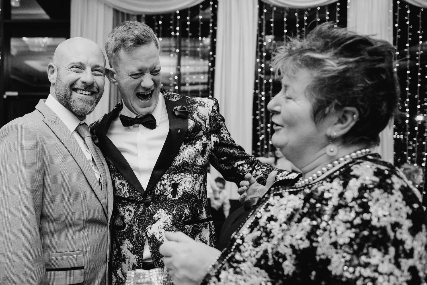 Black and white photo of guests laughing and celebrating at a wedding reception.  Wedding PHOTOGRAPHER Trim Castle