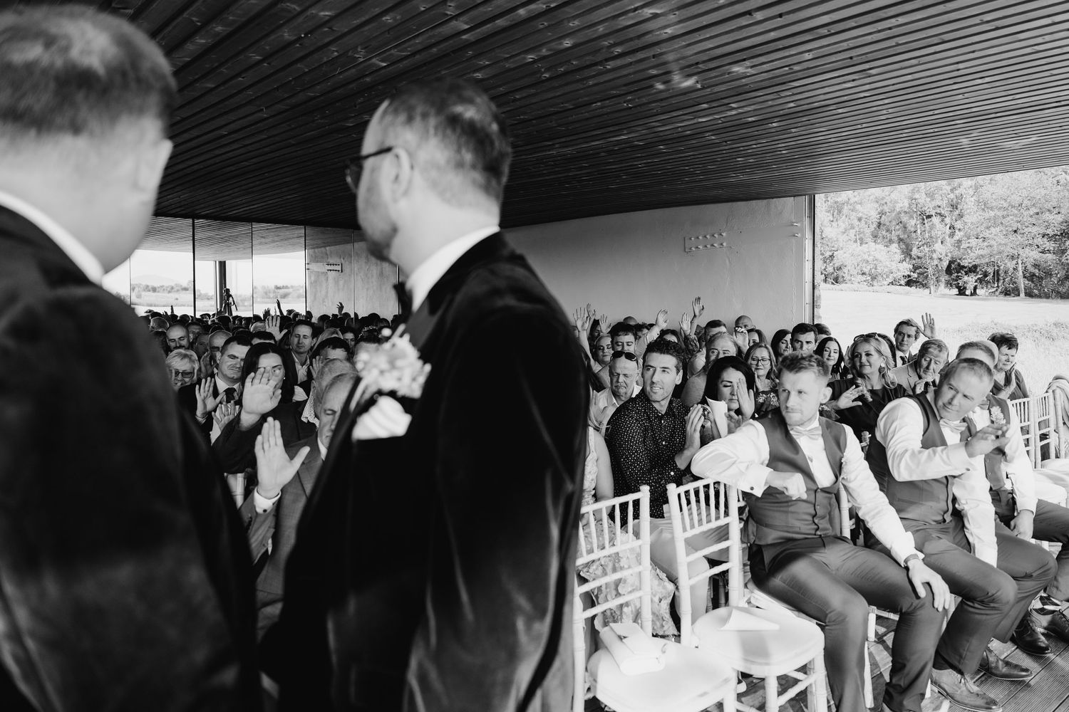 Wedding guests mingling and socializing in a crowded reception venue with draped ceiling decor. LGBTQ Ashley Park Wedding Photographer