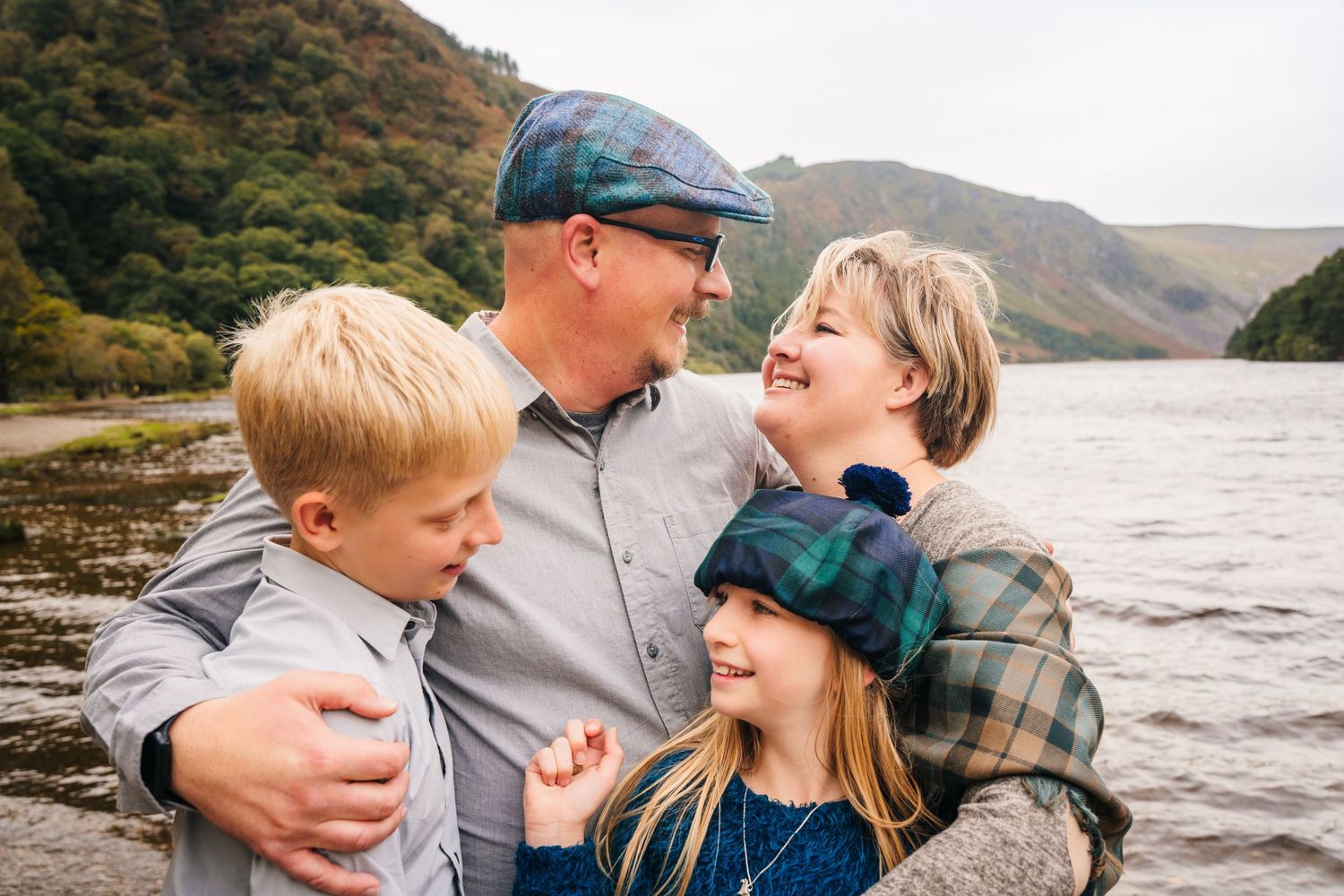 Candid moments of affection captured on a scenic lakeshore with mountains in the distance.Family photogrAPHER DUBLIN