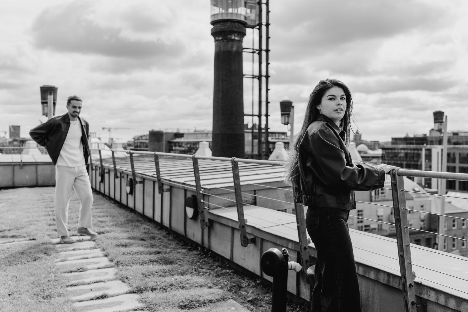 A series of black and white photos showing people walking and posing along an outdoor rooftop or terrace. Couple's Photoshoot PHOTOGRAPHER D
