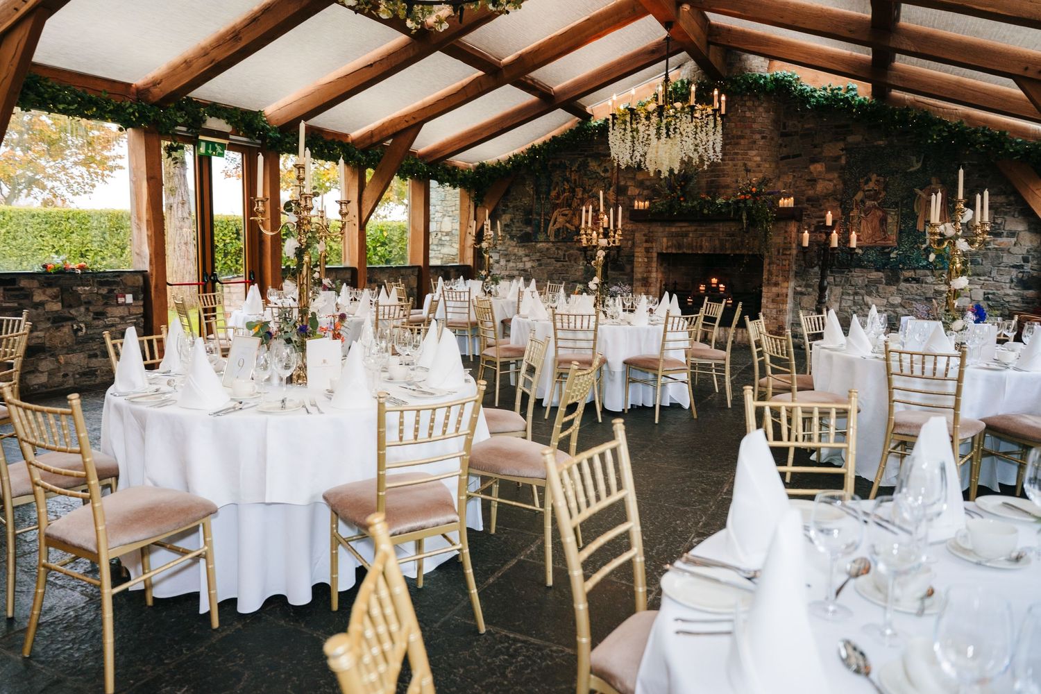 Elegant wedding reception venue with white table settings, wooden beams, and chandeliers.